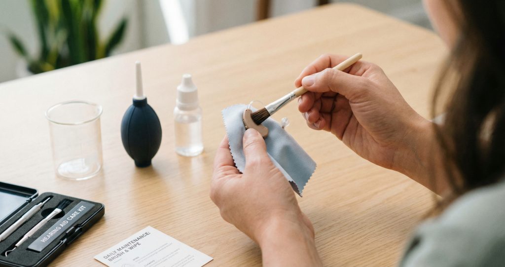 Person cleaning hearing aids with soft cloth